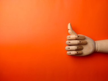 Üst görünüm ahşap el, başparmağı turuncu arkaplanda, metin ve kopya alanı var..