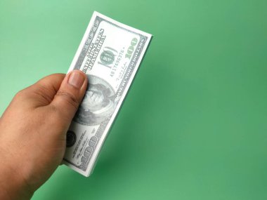 Birisi yeşil arka planda elinde dolar banknotlarıyla fotokopi ve metin tutuyor. İş konsepti..