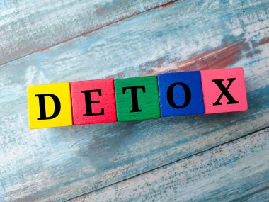 Mavi ahşap arka planda DETOX sözcüğüyle renklendirilmiş tahta küp.