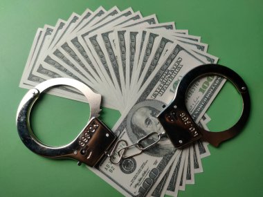 Yeşil arka planda üst görünüm banknotları ve metal kelepçe.