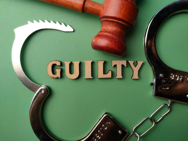 Сверху металлическая манжета и деревянная повязка с текстом GUILTY на зеленом фоне.