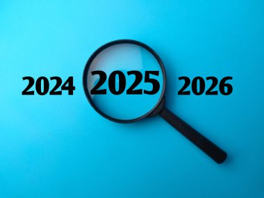 Magnifying glass and 2025 concept with word and blue background. clipart