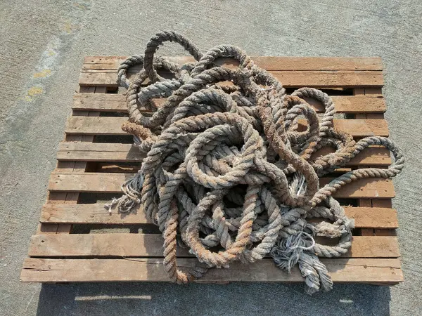 Görüntü, kalın bir halatı, muhtemelen bir demirleme hattını ya da ahşap bir palette dinlenen genel amaçlı ağır bir halatı gösteriyor..