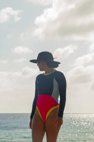 woman in a hat and red bikini standing in the sea