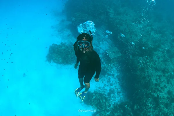 Woman snorkeling with a scuba diver under the ocean.
