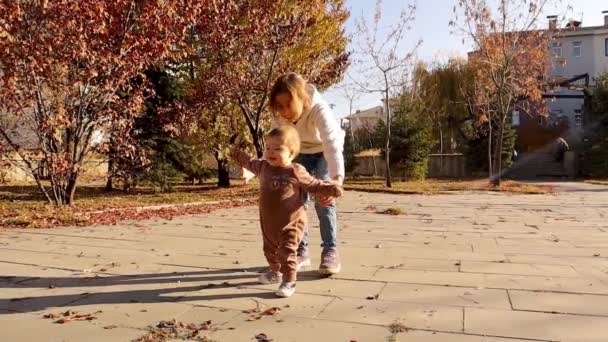 Dítě Učí Chodit Pomáhá Jeho Sestra Malé Nožičky Procházející Podzim — Stock video