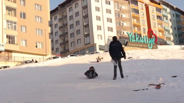 Turkey02 2023のErzurum雪の上にそりを運転している子供たちは斜面をキャップしました そりはナイロンバッグで作られており 子供たちが思い付くためのスマートなアイデアです 子供たちはヤクティエの丘でお互いに楽しみを持っています スキー — ストック動画