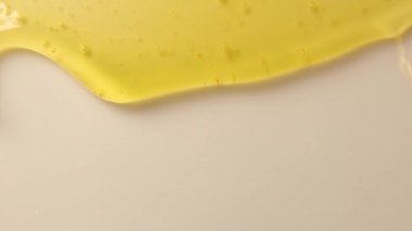 Kalın bir bal sıvısı beyaz bir arkaplanı damlatıyor. Yakın plan sağlıklı organik bal bandırma. Sağlıklı gıda konsepti. İzole edilmiş altın bal damlaları.