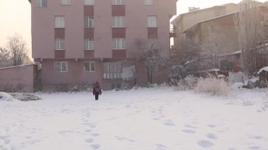 Çocuk sabah saatlerinde soğuk hava için sıcak giyinerek karda yürüyor, Erzurum, Türkiye 'de okula gidiyor. Karlı bir kasabada kışın güzelliğini ve günlük rutini yakalamak. çocuk