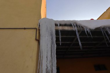 Icicles and frozen snow hanging from a building roof in Erzurum, Turkey, during winter. Temperatures can plummet to -50C, showcasing the extreme cold and harsh winter conditions of the region. clipart