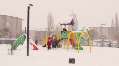 Erzurum, Türkiye. Karla kaplı bir çocuk parkında neşeyle oynayan çocukların iç açıcı sahneleri. Çocuklar eğlenirken bu büyüleyici kış anı karın büyüsünü ve kahkahayı kutluyor.