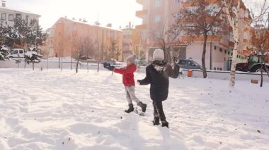 Erzurum, Türkiye ve iki çocuk karda oynayıp gülüyor ve birbirlerine kar atıyorlar. Bu kış harikalar diyarında, soğuk, karlı bir günde, yürek ısıtan ve neşeli bir an..