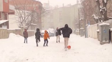 Erzurum, Türkiye, 20 Şubat 2025 'te, çocuklar yoğun kar yağışına rağmen dar bir sokakta futbol oynuyorlar. Karlı dar sokaklar çocukların eğlendiği büyülü bir kış manzarası yaratıyor..