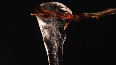 Su damlacıkları eriyen bir buz saçağından siyah bir arkaplana doğru damlıyor, kar erimesini, mevsimsel değişimi ve yaratıcı projeler ve reklamlar için iklim etkisini simgeliyor..