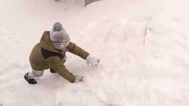 Türkiye 'nin Erzurum kentinde karın keyfini çıkaran çocuk, tamamen karla kaplı bir bahçe merdivenine tırmanmaya çalışıyor. Dengesini kaybediyor ve karın içine düşüyor. Yumuşak kar taneleri düşmeye devam ederken eğleniyor. çocuklar