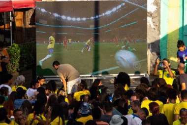 FIFA Dünya Kupası Katarı 2022: Taraftarlar Brezilya ve Sırbistan 'a eşlik etmek üzere Prainha Meydanı' nı doldurdular. 24 Kasım 2022, Rio de Janeiro, Brezilya: Taraftarlar, Brezilya takımının Sırbistan 'a karşı oynadığı maçı izlemek için Gamboa, Rio de Janeiro şehir merkezindeki Prainha Meydanı' nda toplandılar