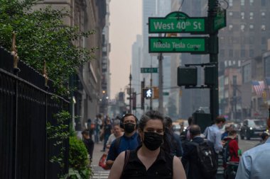 Kanada 'daki orman yangınlarından çıkan duman güneye doğru esiyor ve 7 Haziran 2023, New York, New York, ABD: Maskeli yayalar Kanadalı orman yangınlarından çıkan duman nedeniyle 6. Cadde' ye doğru ilerliyorlar. 