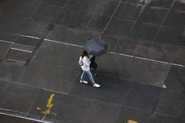 New York, ABD - 24 Ağustos 2023: New York City 'de yağış. Ani hava değişimi beraberinde sağanak yağış getirdi ve New Yorkluları ve turistleri günlük işlerine giderken şemsiyeler ve pançolar ile kendilerini korumaya zorladı.. 