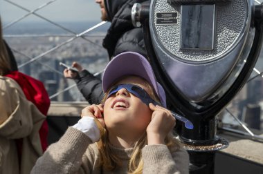 New York 'ta güneş tutulması 2024. 08 Nisan 2024, New York, New York, ABD: Dokuz yaşındaki Nika, Empire State Binası 'nın 86. katındaki Güneş tutulmasını görmek için koruyucu gözlük takıyor 
