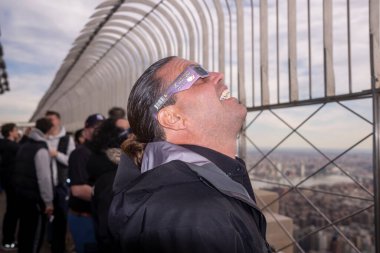 New York 'ta güneş tutulması 2024. 08 Nisan 2024, New York, New York, ABD: Koruyucu gözlük takan bir adam, 8 Nisan 2024 'te New York' ta Empire State Binası 'nın 86. katındaki kısmi güneş tutulmasını izliyor.. 
