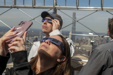 New York 'ta güneş tutulması 2024. 08 Nisan 2024, New York, New York, ABD: Koruyucu gözlük takan bir kadın, 8 Nisan 2024 'te New York' ta Empire State Binası 'nın 86' ncı katındaki güneş tutulmasını izliyor.