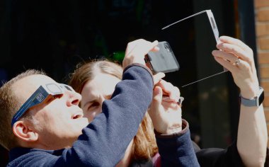 New York 'ta Güneş Tutulması. 08 Nisan 2024, New York, ABD: New Yorklular ve turistler Manhattan 'da güneş tutulmasını izlerken görüldü. Ay, Dünya ile Güneş arasında geçtiğinde bir güneş tutulması meydana gelir.