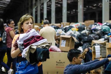 Passo Fundo (RS), 05 / 11 / 2024 - Passo Fundo kentindeki bir toplama sahasında giysileri sınıflandıran kadın, bu Cumartesi (11), sağanak yağış mağdurlarına yapılacak bağışları organize etmek için