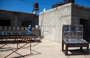 (INT) Palestinian Enas Al-Ghoul worked on inventing two devices to facilitate cooking food using the sun's rays for Palestinians. September 3, 2024, Khan Yunis,  Gaza, Palestine: Palestinian agricultural engineer Enas Al-Ghoul works on the roof f he clipart