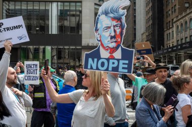 Protestocular koz yönetimini kınamak için ülke çapında şehirlerde toplandılar. 19 Nisan 2025, New York, New York, ABD: İnsanlar protestolara katılırken Başkan Donald Trump 'ın karikatürünü tutarken bir kişi selfie çekiyor. 