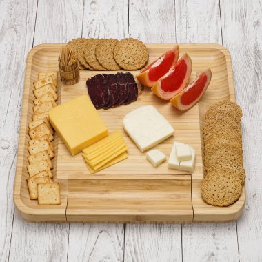 Atıştırmalıklı peynir tahtası: ahşap arka planda meyveli, şekerli ve etli farklı çeşitte sert ve yumuşak peynir.