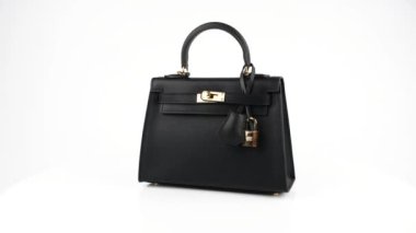 Video 4K çözünürlükte. Beyaz arka planda izole edilmiş siyah deri çantanın 360 dönüşü..