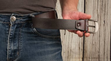 Yakışıklı adam mavi kot pantolon ve kahverengi gerçek deri kemer giyiyor. Yakın plan.