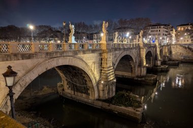 A breathtaking evening scene of St. Angelo Bridge near the iconic Castel Sant'Angelo in Rome, Italy. The statues glow under spotlights, creating a magical atmosphere. A must-see for tourists! clipart