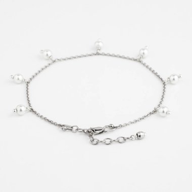 Beyaz arka planda kolyesi ve incileri olan zarif gümüş bir bilezik.