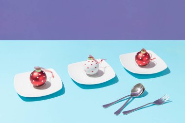 Beyaz tabak ve kaşıklarda üç noel puanı ve parlak mavi ve mor arka planda çatal. Asgari Noel ya da yeni yıl kutlaması konsepti. Yaratıcı tatil tablosu bileşimi.