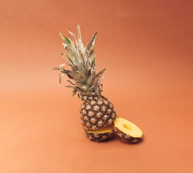 Ananas büyük bir rulo yiyor. Minimum tasarım. Kahverengi arkaplan.