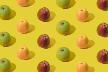 Sarı pastel arka planda yeşil, sarı ve kırmızı elma. Desen.