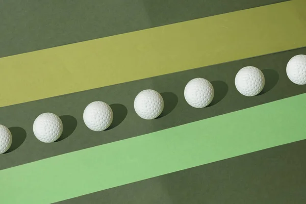 在绿色粉刷的背景上布置好的白色高尔夫球 带复制空间的极小模式 — 图库照片