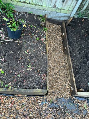 Tahta döşeme ile yükseltilmiş bahçe projesinin peyzajı sınır organik büyüyen alanlara kenar, yol üzerinde çakıllarla kaplı kara zemin örtüsü açık araziyi tamamlamak için.