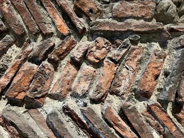 Close up of ancient thin red building bricks with grey mortar design herringbone pattern part of ancient historical Roman castle wall in Essex England uk
