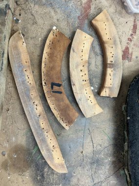 Close up of handmade timber frame chair in pieces being mended with new wood dowels set and glued drill holes re construct the vintage wood seat before upholstery by craftsman in workshop flat lay
