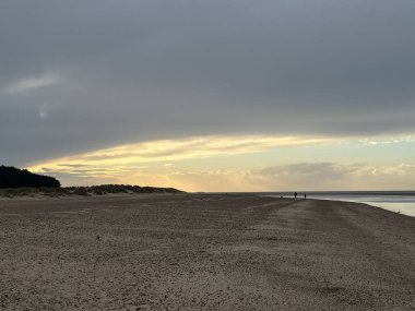 Gün batımında kumlu kumsalın güzel manzarası durgun deniz kum tepeleri ve gri mavi ince bulut gökyüzü ile yaz başında Norfolk Doğu Anglia 'daki denizin hemen yanında hiç kimse