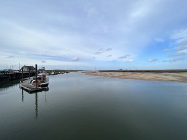 Huzurlu liman manzarasının güzel deniz manzarası Wells 'te okyanusun ufuk çizgisine Norfolk' ta Doğu Anglia 'da deniz manzarası mavi gökyüzü açık bulutlar bahar akşamı demirlemiş teknelerle suları yansıtıyordu.