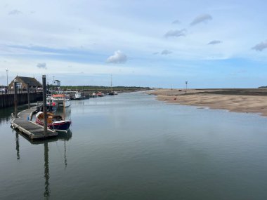 Huzurlu liman manzarasının güzel deniz manzarası Wells 'te okyanusun ufuk çizgisine Norfolk' ta Doğu Anglia 'da deniz manzarası mavi gökyüzü açık bulutlar bahar akşamı demirlemiş teknelerle suları yansıtıyordu.