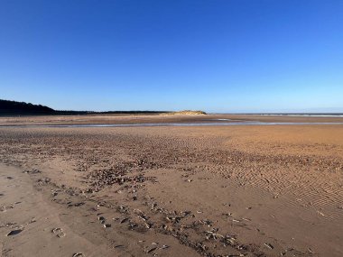 Parlak güneşli bir kış gününde ufuk açılacak engin kumlu bir sahilin güzel manzarası. Wells 'te mavi gökyüzü. Norfolk' ta, Doğu Anglia 'da deniz.