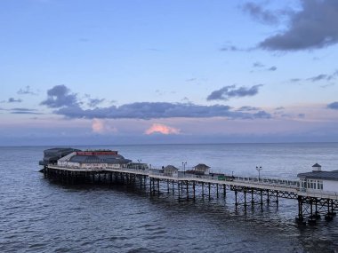 Cromer İskelesi 'nin ve deniz ufkunun güzel gün batımı manzarası Norfolk Doğu Anglia kumlu sahilde ve sakin, eski, eski, ahşap iskelenin sakin suları sakin okyanus bayramına doğru