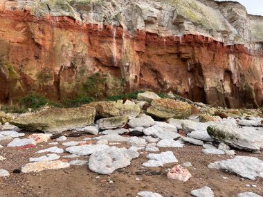 Hunstanton plajındaki tarih öncesi uçurum manzarası milyonlarca yıllık katmanlar halinde beyaz ve pas renginde oluşumlar ve güzel bir bahar gününde kayalara sıkışmış fosiller. 