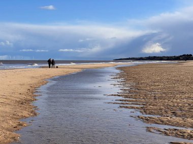 Beyaz kumlu sahil manzarası sersemletici. Dalgalar kıyıdan ufka akan nehir. Mavi gökyüzünde yürüyen çift sakin deniz ve beyaz bulut. 