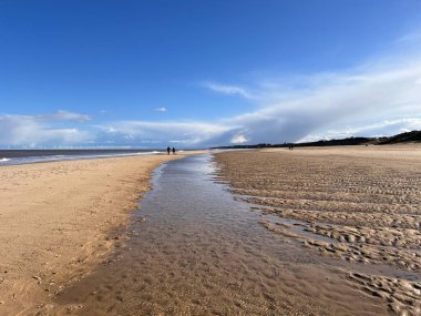 Beyaz kumlu sahil manzarası sersemletici. Dalgalar kıyıdan ufka akan nehir. Mavi gökyüzünde yürüyen çift sakin deniz ve beyaz bulut. 