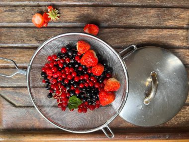 Taze toplanmış çileklere yakın kırmızı frenk üzümleri, olgun meyveler, sulu meyveler organik kır bahçesinde yetişen organik kevgire benzeyen düz bir manzarası var.